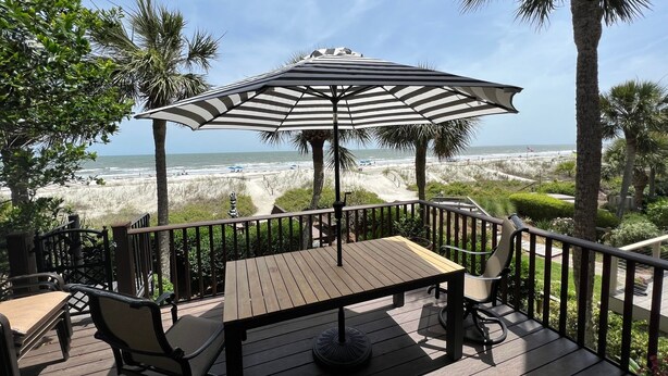 A wooden deck with a table and chairs, overlooking a beach with dunes and palm trees. - 29 Turtle Lane Club: BESTNEST by Beverly Serral OCEANFRONT (Hilton Head Island)