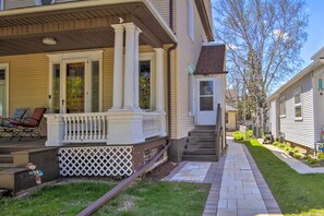 Traditional home with a front porch and gabled roof, set amidst a well-manicured lawn.