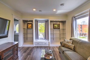 Relax in this stylish living room with a large window offering a view of the surrounding area, a bench, and a flat-screen TV.