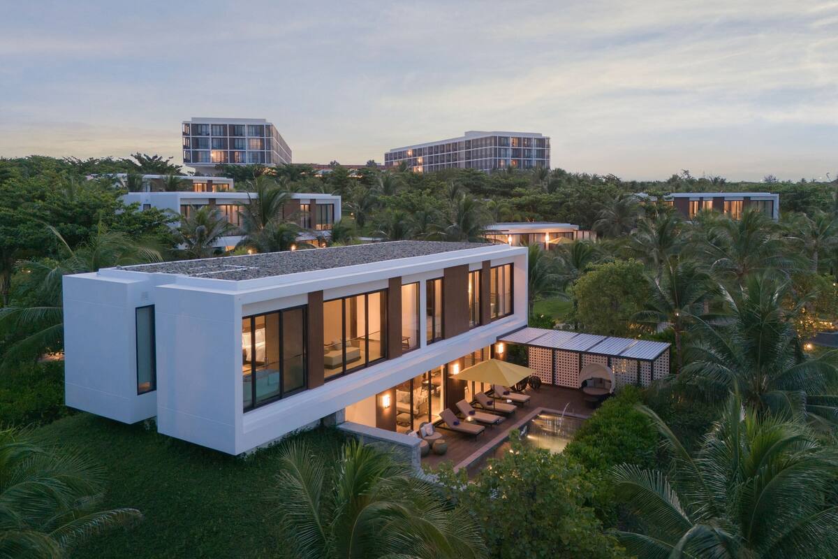 A modern, multi-story building with large windows, a rooftop terrace, and a pool area.