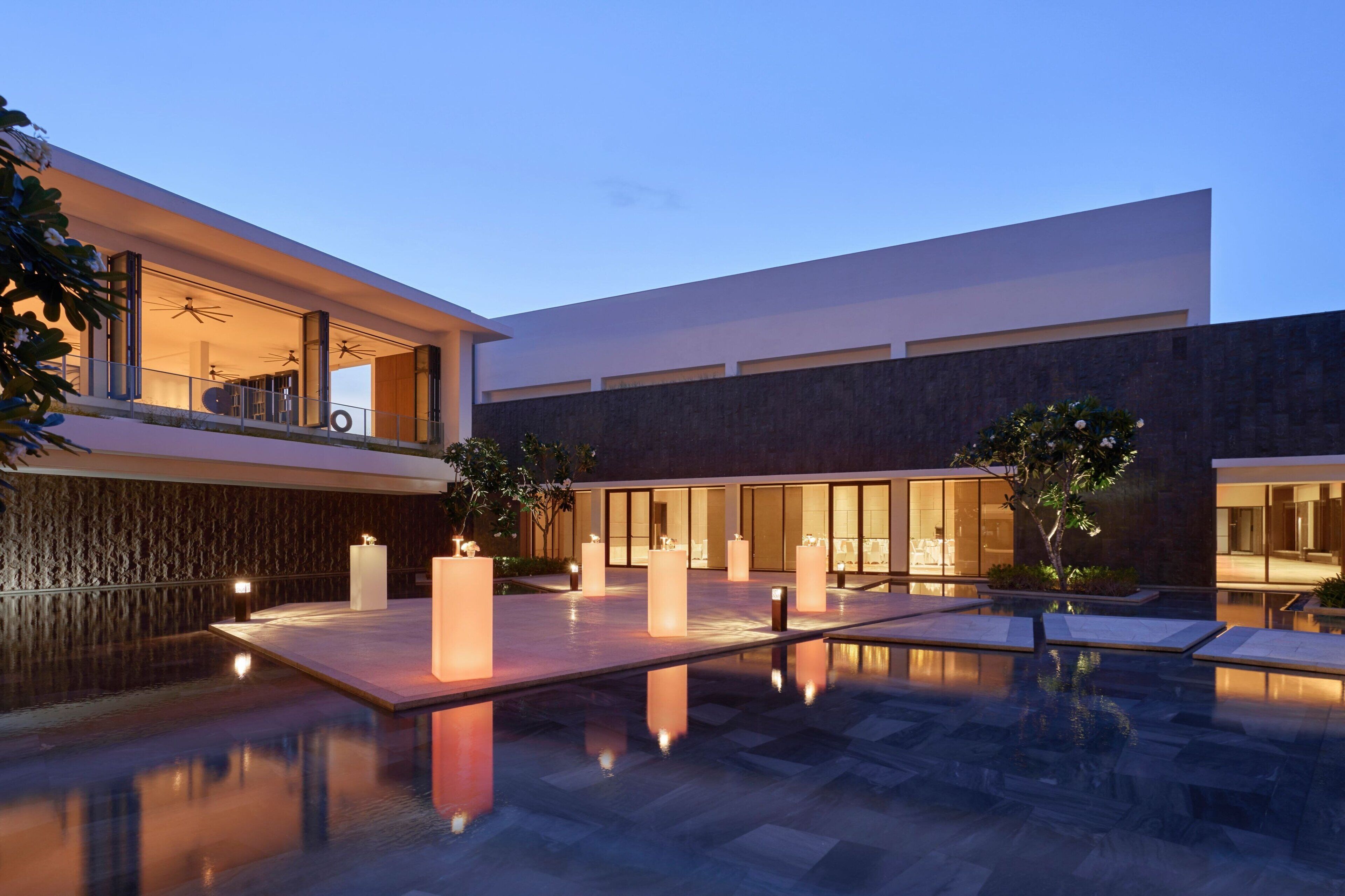 A modern building with a pool, outdoor lighting, and a well-maintained garden area.