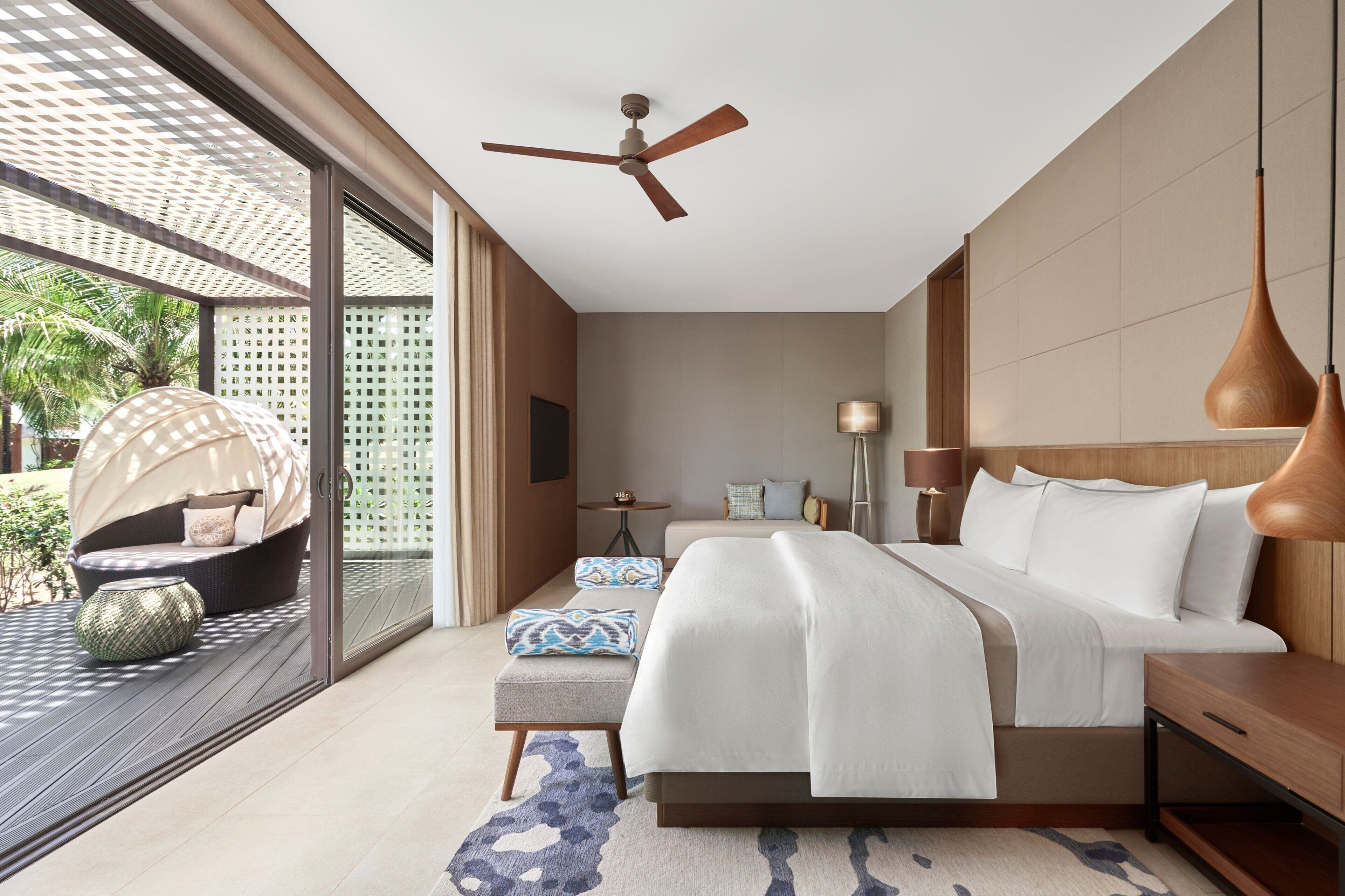 Un dormitorio moderno con una cama grande, ventilador de techo y vista al exterior.