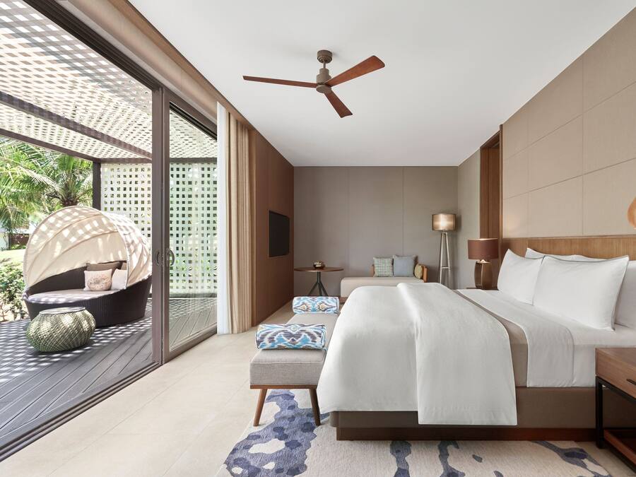 Un dormitorio moderno con una cama grande, ventilador de techo y vista al exterior.