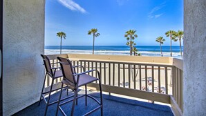 Een balkon met uitzicht op de oceaan en palmbomen.