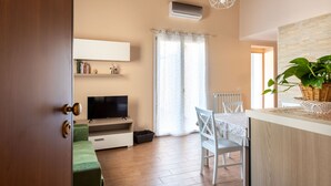 Una sala de estar moderna con una televisión de pantalla plana, una mesa de comedor y un gran ventanal con cortinas.