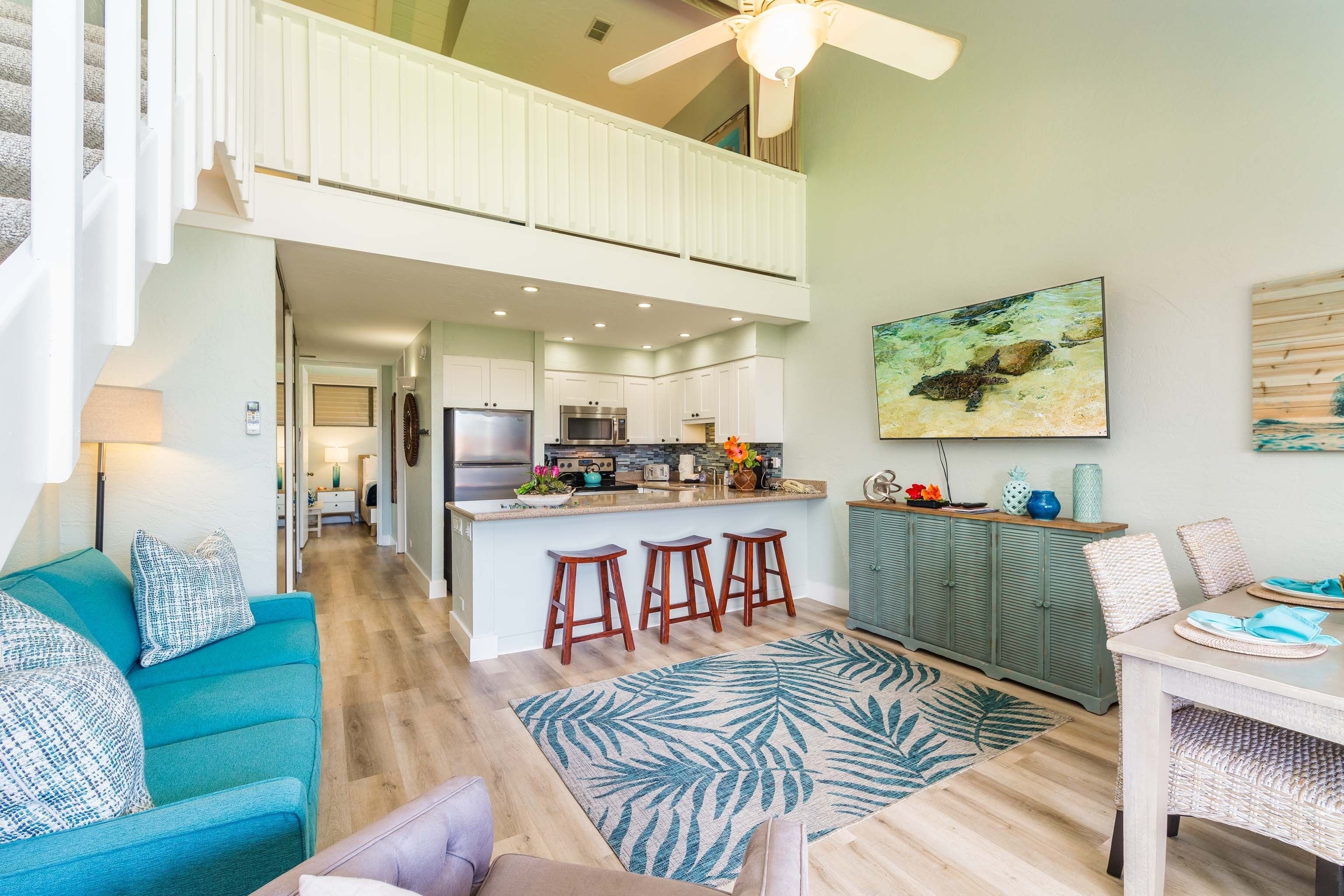 A spacious living area with a high ceiling, a kitchen with a bar, and a dining area.