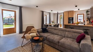Ein modernes Wohnzimmer mit einer Couch, einem Esstisch und einer Küchenzeile.