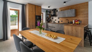Eine moderne Küche mit Holzschränken, einer zentralen Kochinsel und einem Essbereich mit Holztisch und Stühlen.