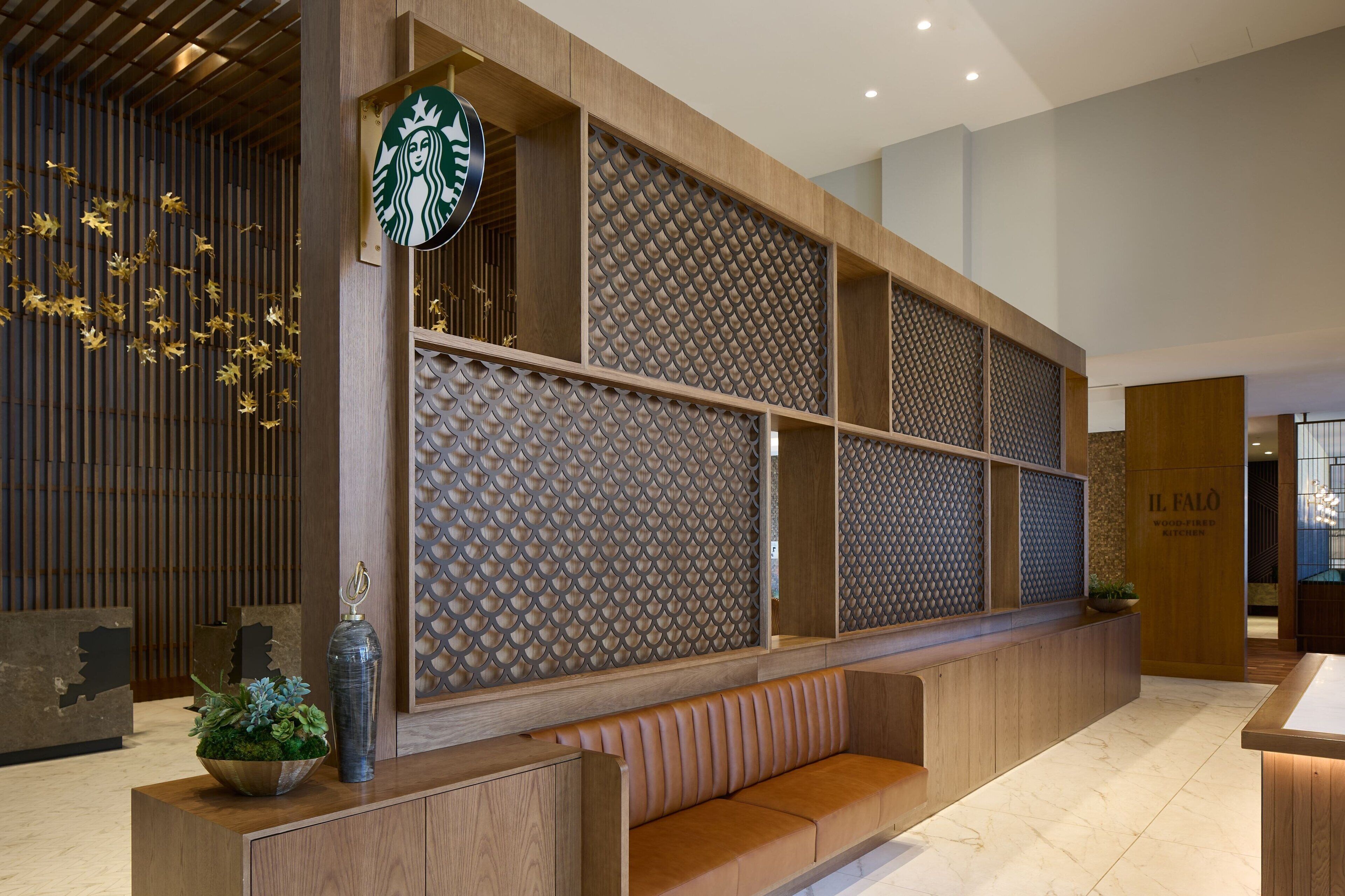 A modern reception area with a wooden reception desk, a Starbucks logo, and a patterned wall.