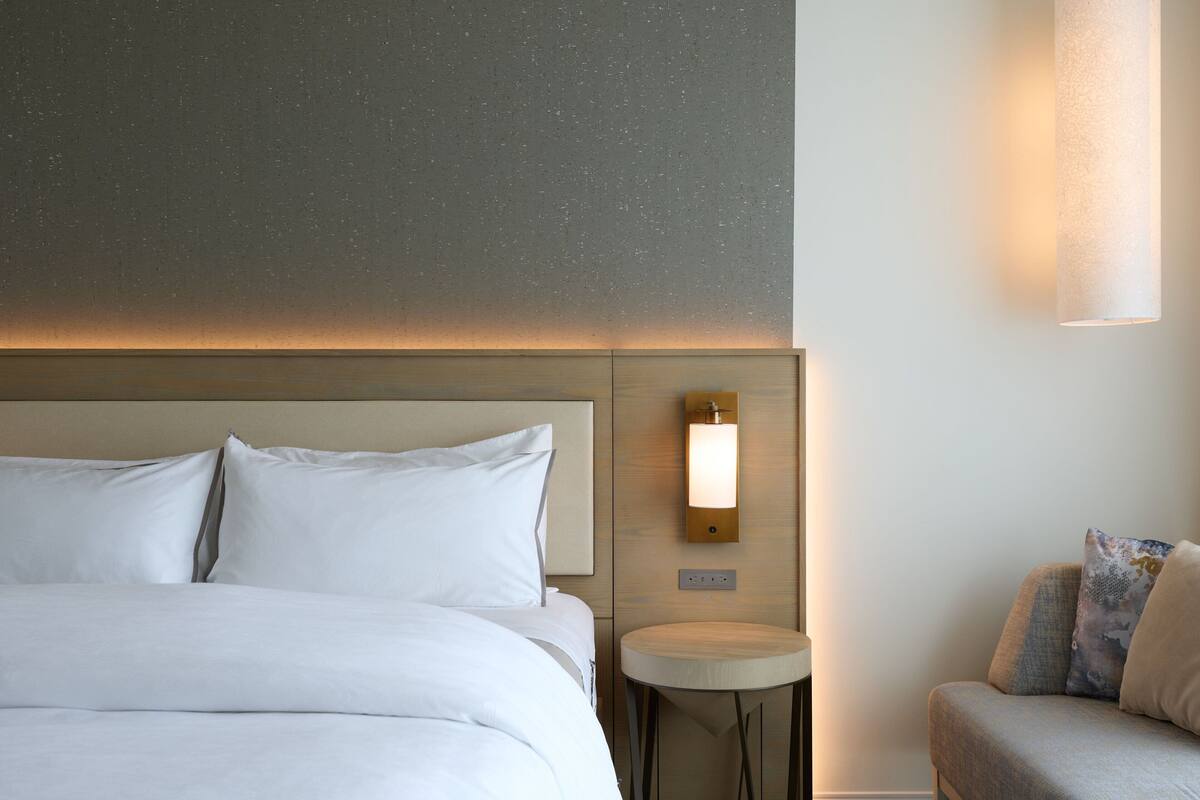 A hotel room with a large bed, a small round table, and a sofa.