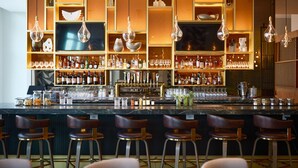 Zona de bar con varias estanterías llenas de botellas, vasos y una barra.