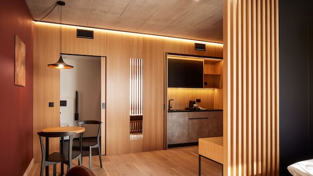 Un intérieur moderne comprenant un espace repas en bois, une kitchenette et un lit.