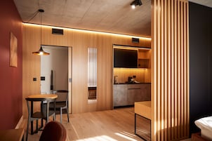 Un interior moderno con una zona de comedor de madera, una kitchenette y una cama.