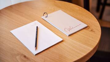 A wooden table with two white notepads and a pen.