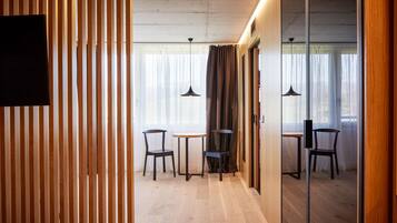 A modern room with wooden slats, a small round table, two chairs, and a large mirror.
