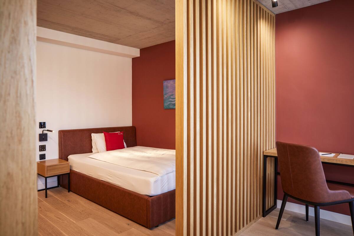 A bedroom with a wooden bed, a desk, and a chair.