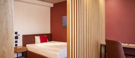 A bedroom with a wooden bed, a desk, and a chair.