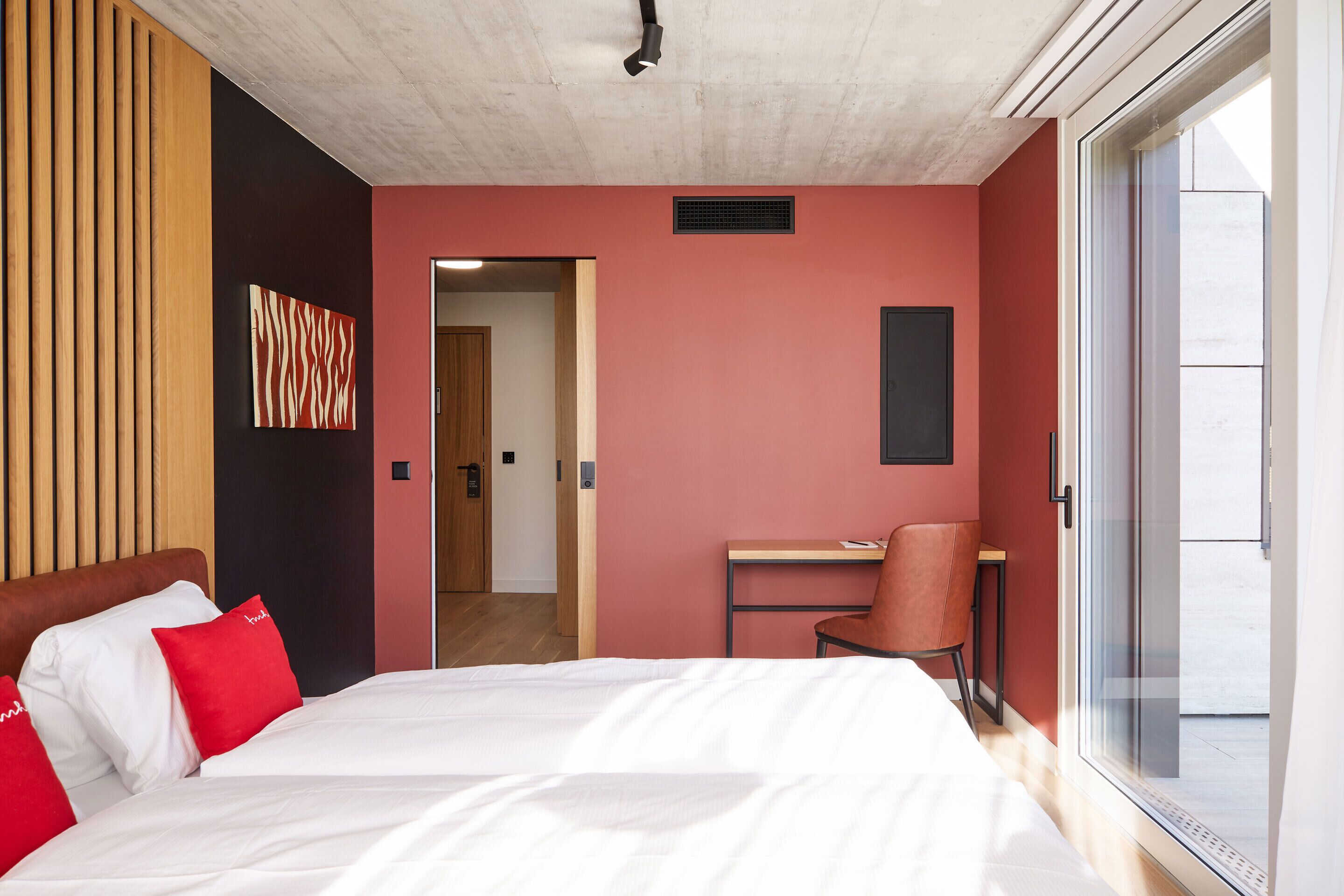 A modern hotel room with a bed, a desk, and a chair.