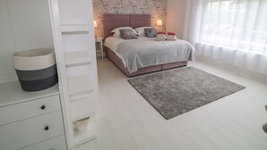 A bedroom with a bed, nightstands, a grey rug, and a wardrobe. - Wee Andy's (Buncrana)