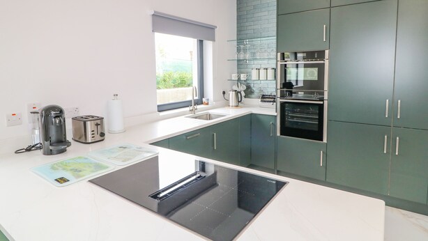 A modern kitchen with a built-in stove, oven, and sink. - Wee Andy's (Buncrana)