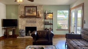 A living room with a stone fireplace, leather armchair, and a sofa. - Sunnyside | Fire Pit | Spacious & Comfortable (Fredericksburg)