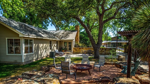 A house with a patio area featuring outdoor furniture, a fire pit, and a stone wall. - Sunnyside | Fire Pit | Spacious & Comfortable (Fredericksburg)