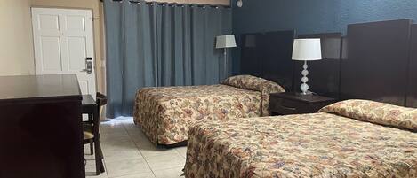 A hotel room with two beds, a desk, and a chair.