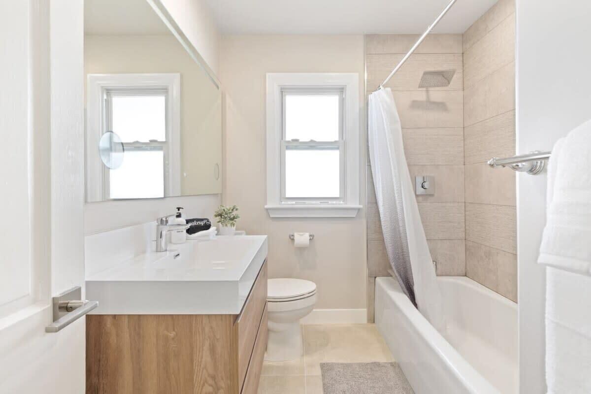 Een moderne badkamer met een witte wastafel, toilet en bad.