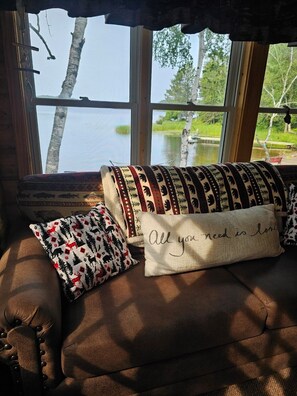 A cozy seating area with a view of a lake and trees.