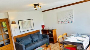A living room with a sofa, a coffee table, and a dining table set for four.