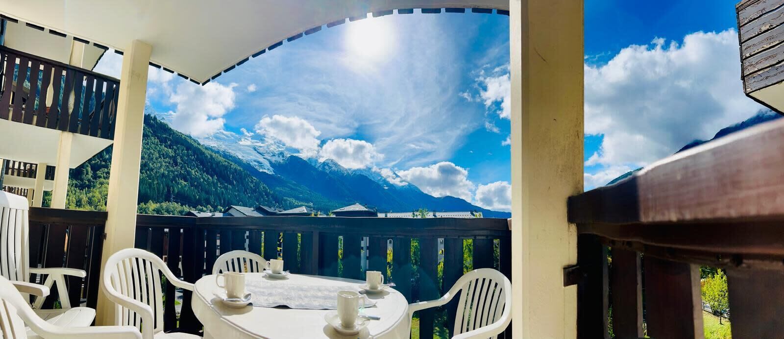 Un espace extérieur abrité, avec une table et des chaises, offrant une vue sur un paysage montagneux.