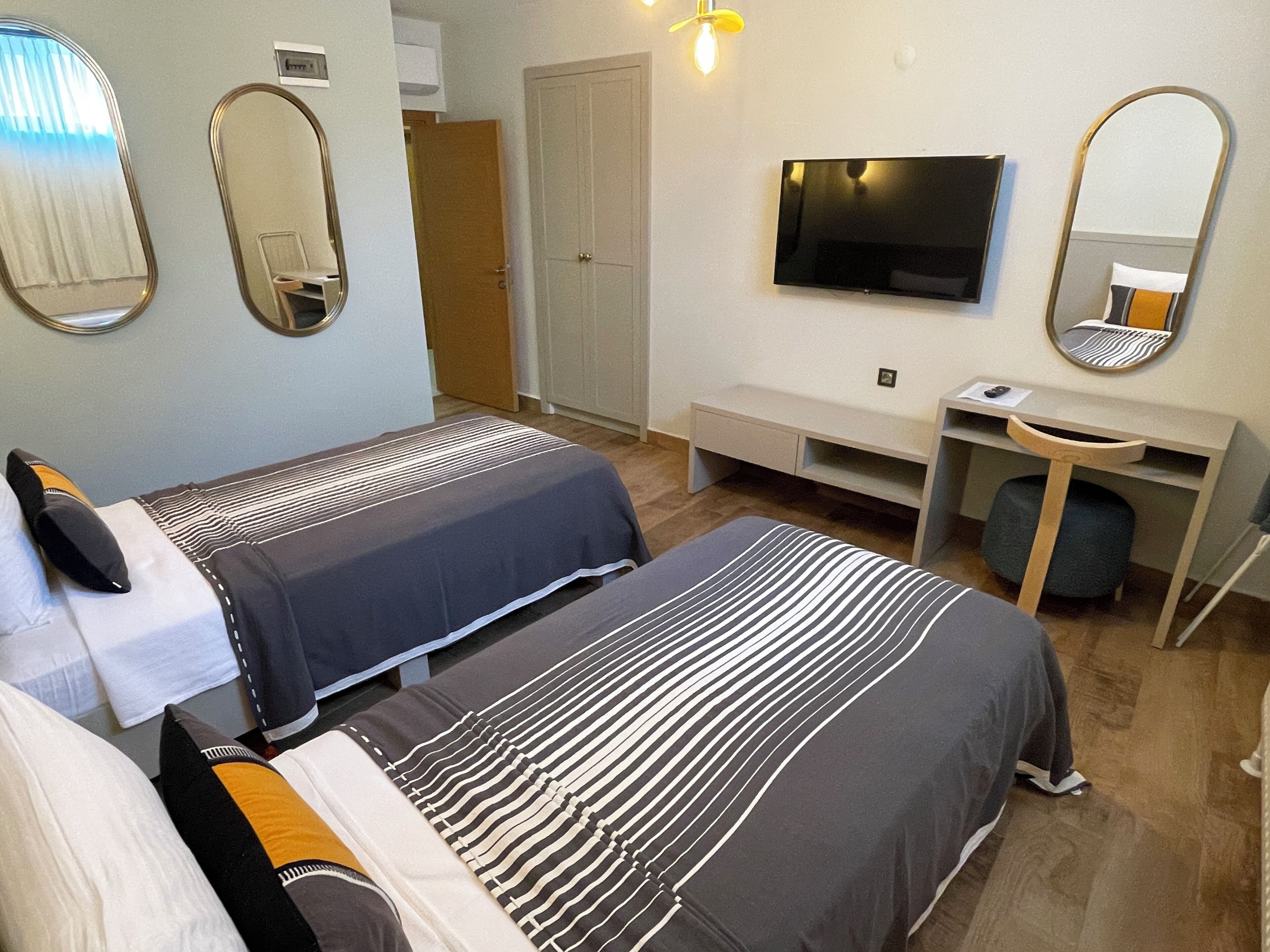 Une chambre d’hôtel avec deux lits, une télévision, un bureau et un miroir.