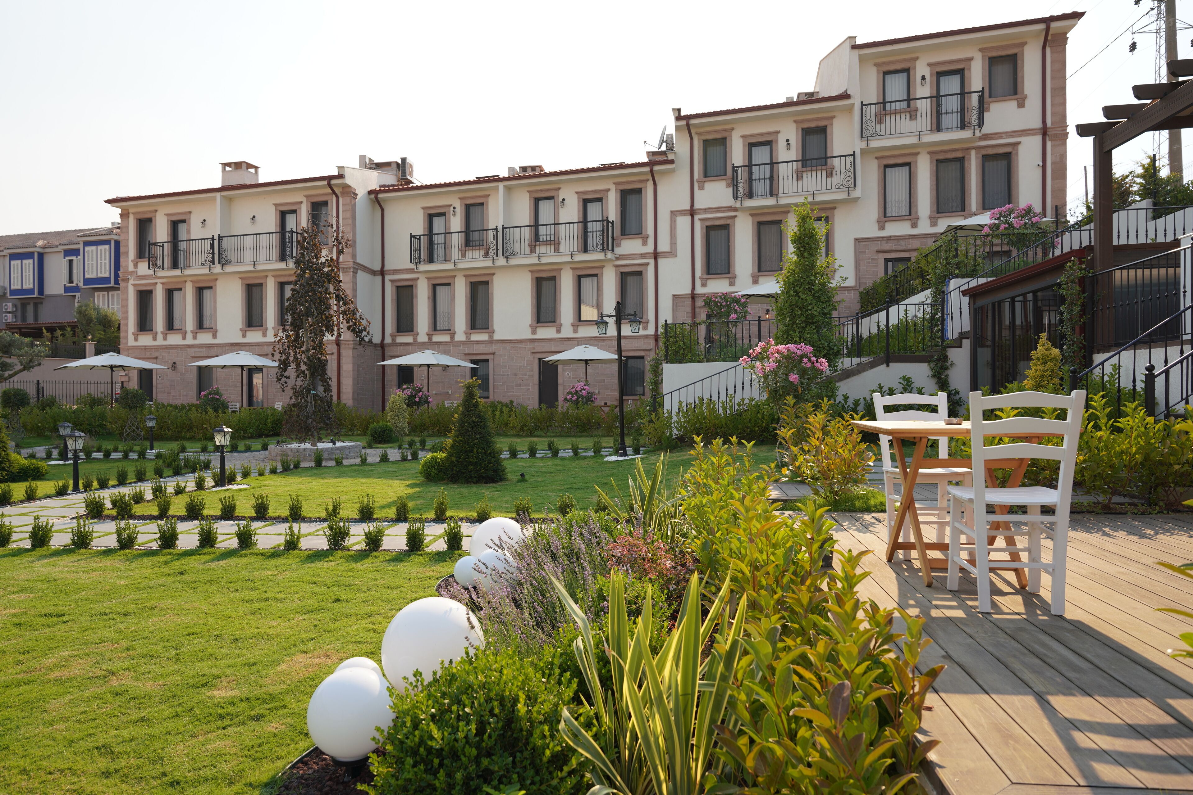 A courtyard with a wooden deck, white chairs, and a table.