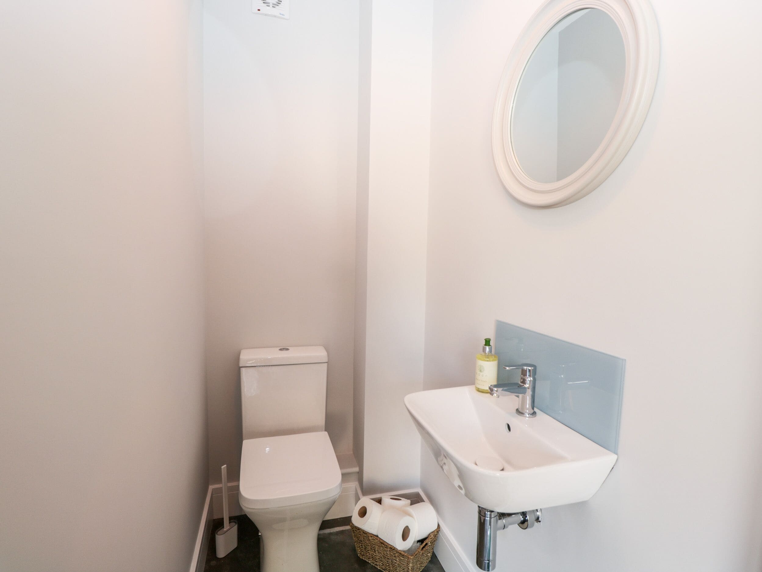 A small, white bathroom with a toilet, a sink, and a mirror.