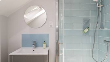 A bathroom with a white sink, a mirror, and a shower with blue tiles.