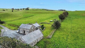 A stone farmhouse with a paved driveway and a car parked in front. - Orsedd Wen Cottage (Llanrwst)