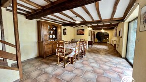 A dining area with a long table, wooden chairs, and a cabinet with dishes. - Domaine de La Calm: In a nature park with breathtaking views of the Pyrenees (Villardonnel)