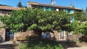 A stone building with a rustic charm, featuring a wooden bench and potted plants in the foreground. - Domaine de La Calm: In a nature park with breathtaking views of the Pyrenees (Villardonnel)