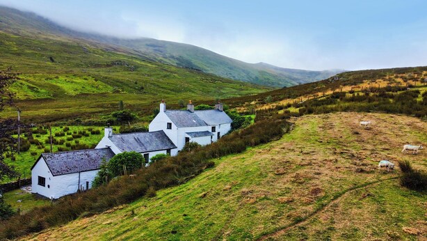 A white house with multiple chimneys, surrounded by a grassy landscape and sheep grazing. - Cwm (Betws-Y-Coed)
