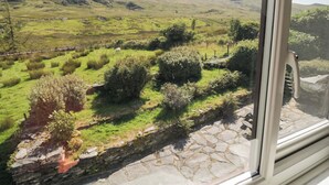 A view from a window overlooking a green landscape with a stone wall and a sheep grazing. - Cwm (Betws-Y-Coed)