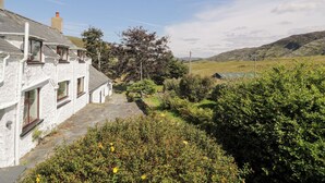 A white stone building with multiple windows and a stone pathway leading to a green field. - Cwm (Betws-Y-Coed)