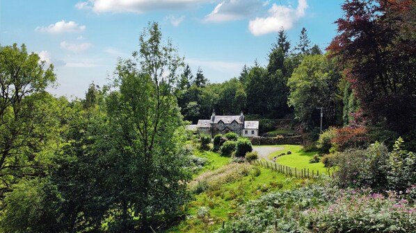 A traditional stone house surrounded by lush greenery and a well-maintained garden.