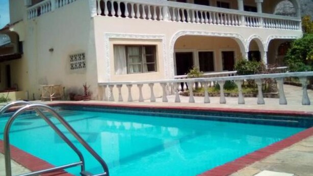 Un edificio de dos pisos con piscina, que cuenta con un balcón con barandilla y un patio cubierto.