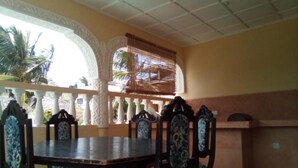 Comedor con mesa y sillas, techo decorativo y vista a palmeras afuera.