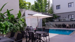 An outdoor patio area with a pool, surrounded by modern furniture and lush greenery. - Urban Hotel and Spa (Kenitra)