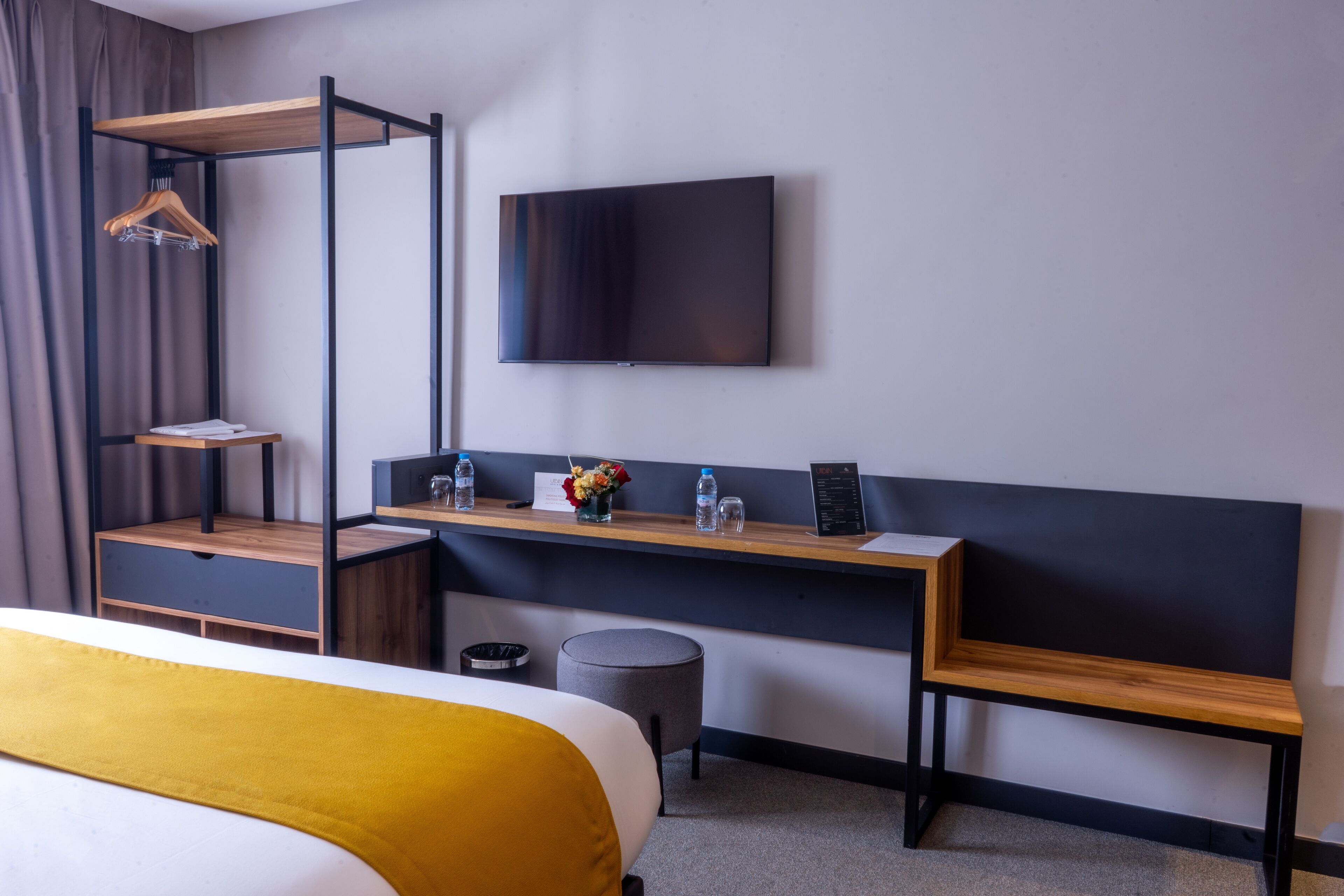 Una camera d'albergo moderna con un letto, una scrivania con una sedia, una TV e un armadio a muro.