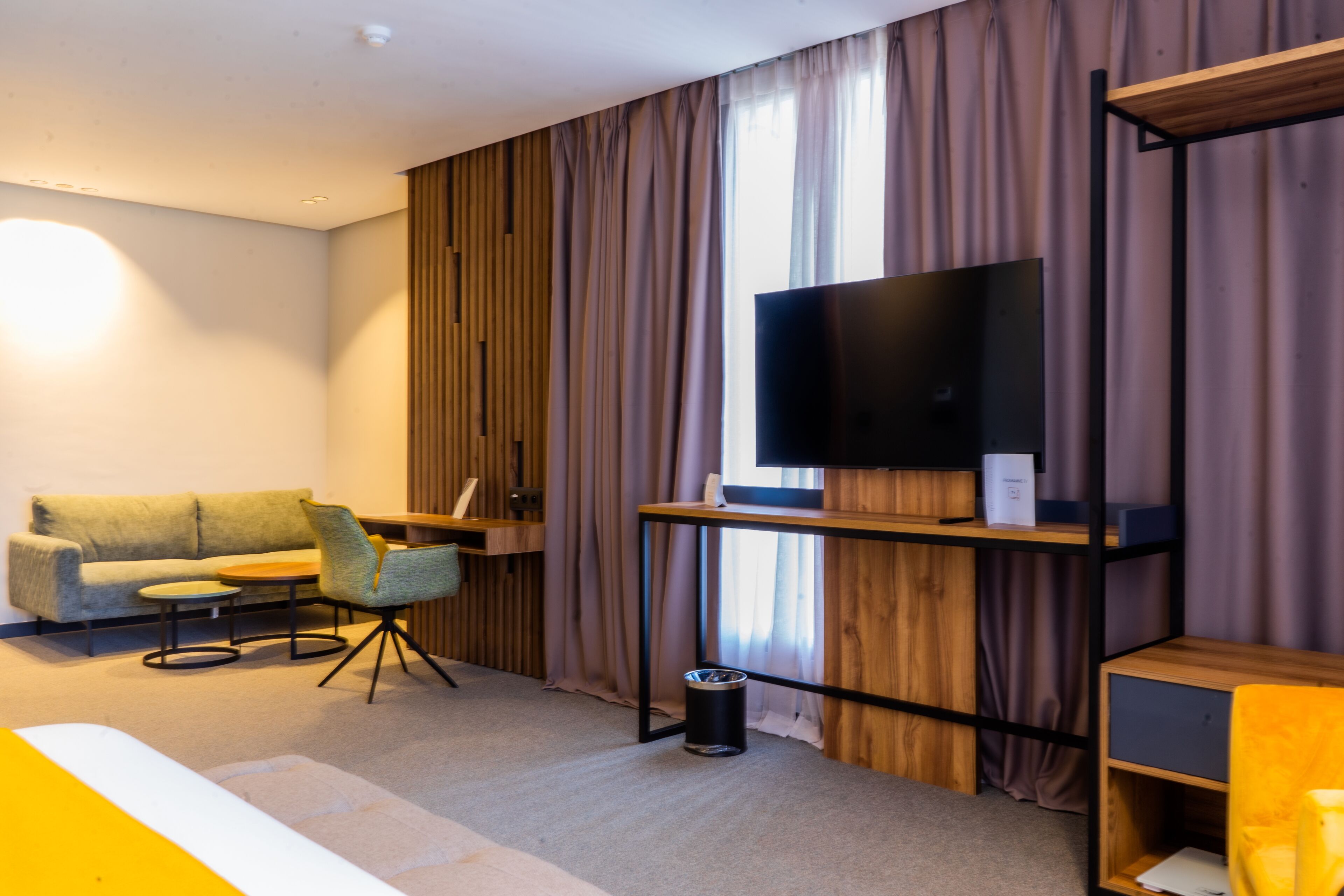 Una sala de estar moderna con sofá, sillón, mesa de centro y televisor sobre un soporte de madera.