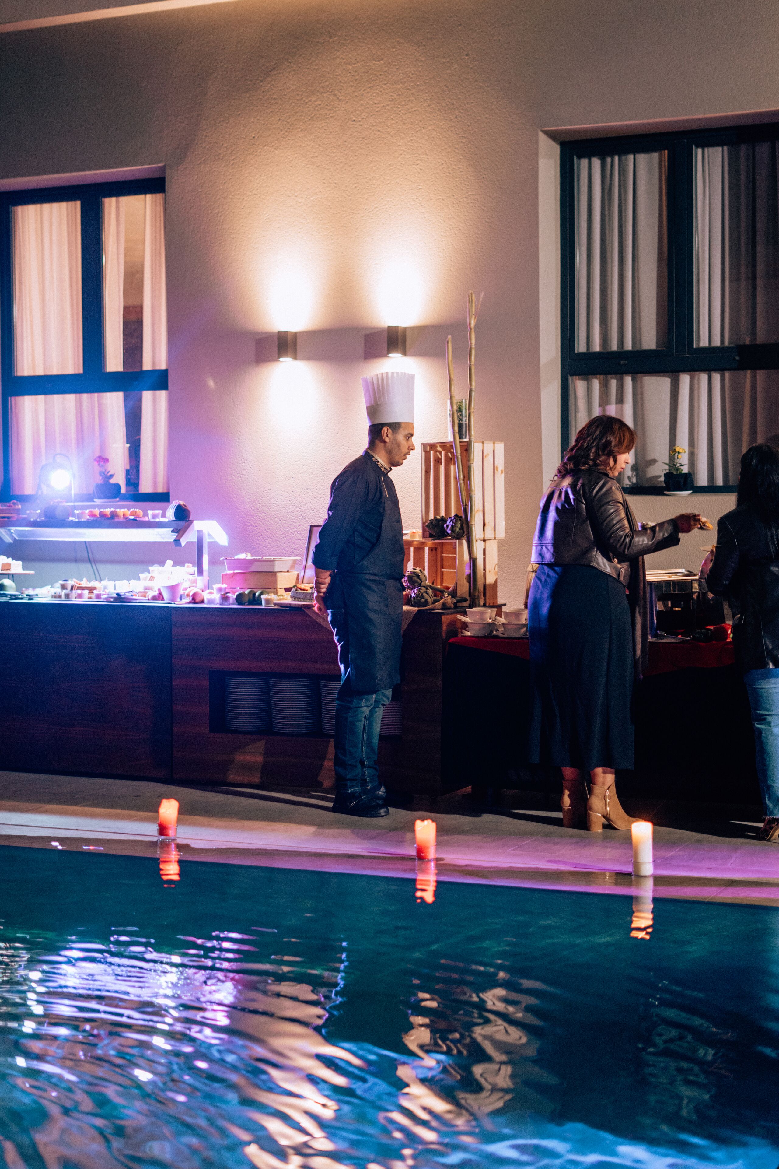 A poolside bar area with a counter, candles, and a person serving.