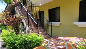 A multi-story building with a yellow facade, black railings, and a staircase leading to the upper floors.