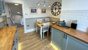 A modern kitchen with a wooden countertop, a built-in toaster, and a wall-mounted clock.
